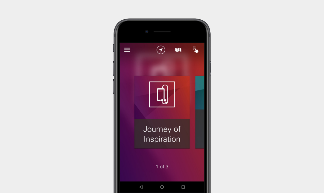 A black smartphone centered on a light gray background. On the phone screen is a modern app interface with a blurred purple-red gradient background. At the top are white icons for a menu, compass/navigation, map, and touch/interaction. In the center is a large card featuring a white line icon of a phone and cable, with the title "Journey of Inspiration" beneath it. Near the bottom, small text reads "1 of 3."
