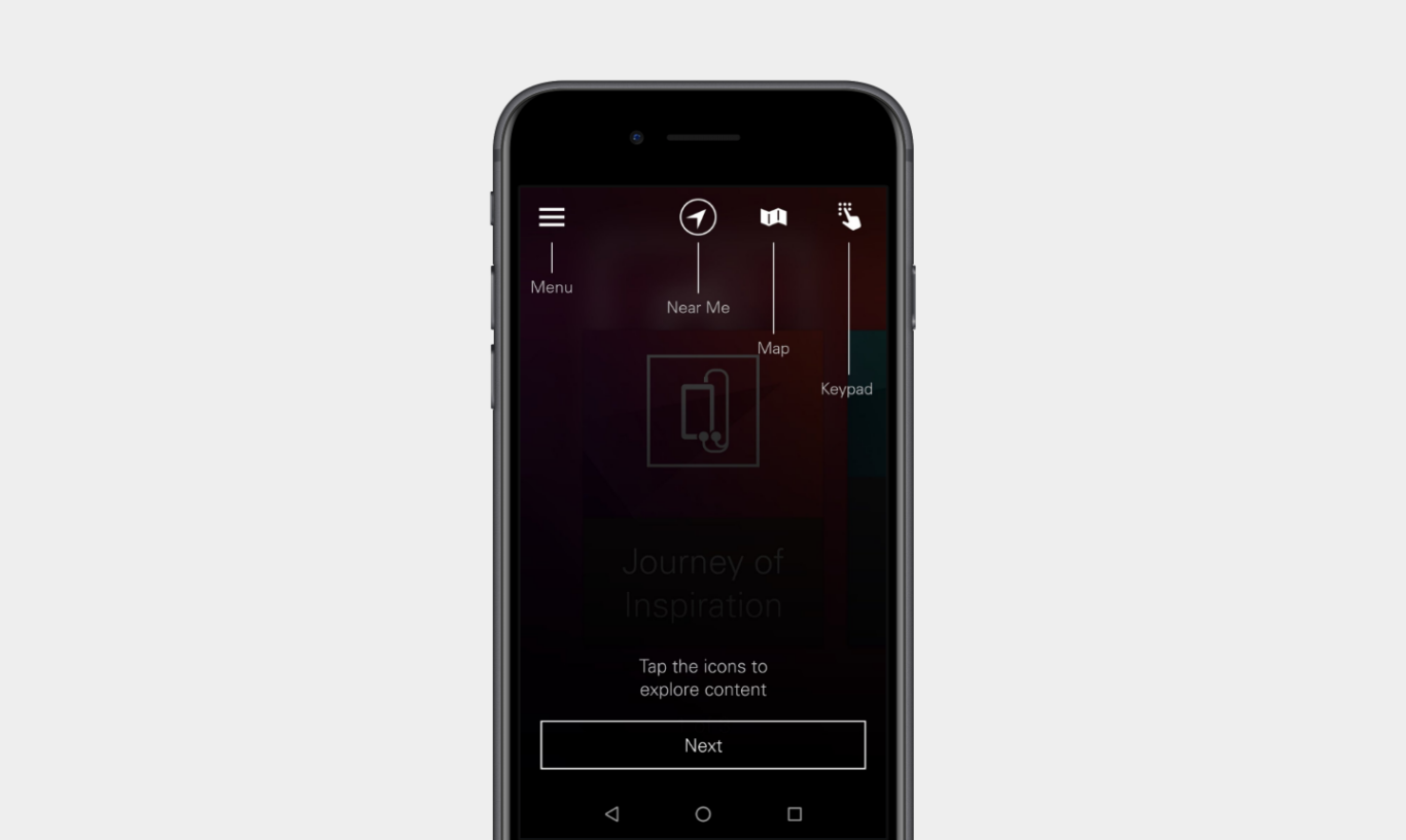A black smartphone centered on a light gray background. On the phone screen is a dimmed app interface with a tutorial overlay. At the top are four white icons with vertical guide lines and labels: a hamburger icon labeled "Menu," a compass/arrow icon labeled "Near Me," a folded map icon labeled "Map," and a hand/keypad icon labeled "Keypad." In the middle of the screen, faint text reads "Journey of Inspiration," and near the bottom it says "Tap the icons to explore content." A rectangular outlined button labeled "Next" appears below the instruction text. The overall UI is dark, with muted red and purple tones in the background.